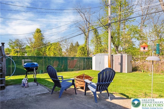view of patio featuring an outdoor structure, fence, a grill, an outdoor fire pit, and a storage shed