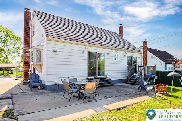 back of house featuring a patio, a fire pit, a chimney, and fence