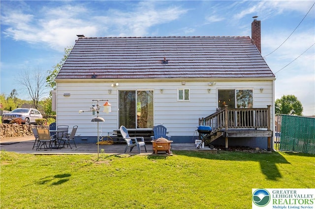 rear view of property featuring fence, a chimney, a patio area, a lawn, and an outdoor fire pit