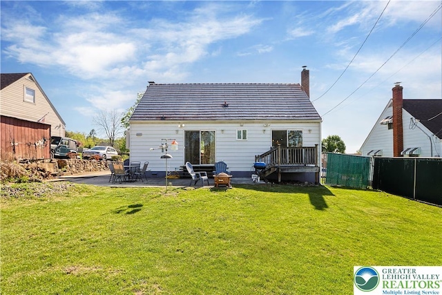 rear view of house with a lawn, a patio area, fence, and a chimney