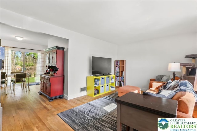 living area featuring baseboards, visible vents, and light wood finished floors