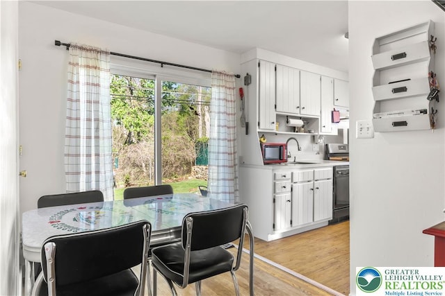 kitchen with open shelves, a sink, light countertops, white cabinetry, and light wood-type flooring