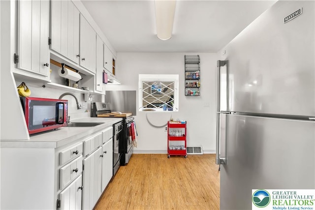 kitchen with visible vents, appliances with stainless steel finishes, light wood-type flooring, light countertops, and white cabinets
