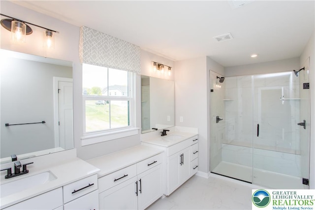 full bath with a sink, two vanities, a stall shower, and marble finish floor