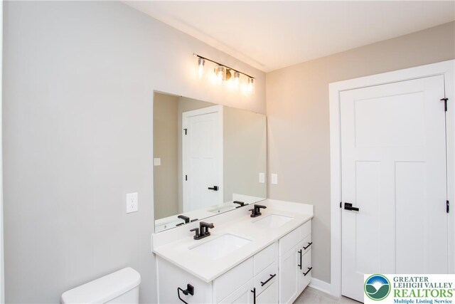 bathroom featuring double vanity, a sink, baseboards, and toilet