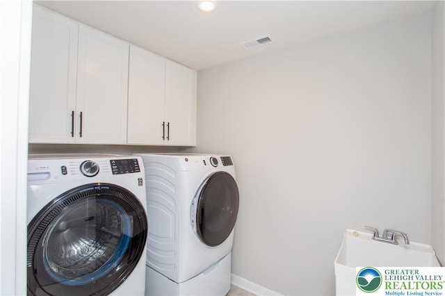 clothes washing area featuring visible vents, cabinet space, baseboards, and washer and dryer