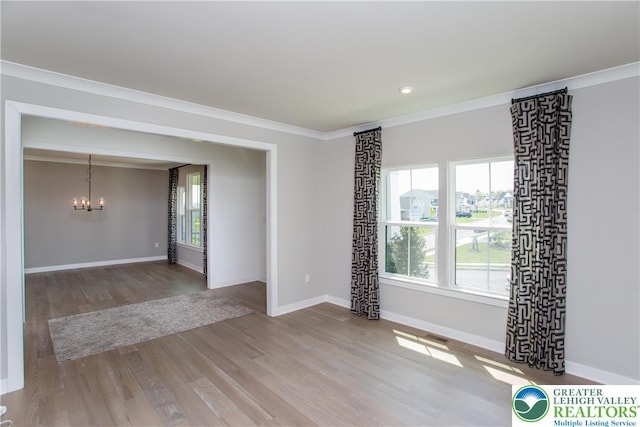 spare room with an inviting chandelier, recessed lighting, baseboards, wood finished floors, and ornamental molding