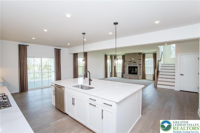 kitchen with a sink, light wood finished floors, a brick fireplace, stainless steel appliances, and open floor plan