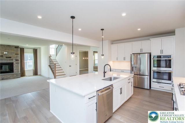 kitchen featuring a sink, light wood-style floors, light countertops, stainless steel appliances, and open floor plan