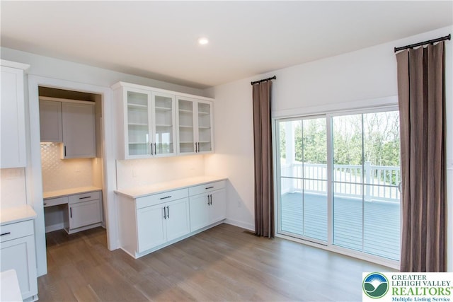 kitchen with light countertops, wood finished floors, white cabinets, and glass insert cabinets