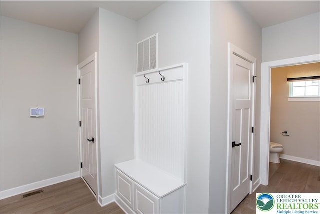 mudroom featuring baseboards, visible vents, and wood finished floors