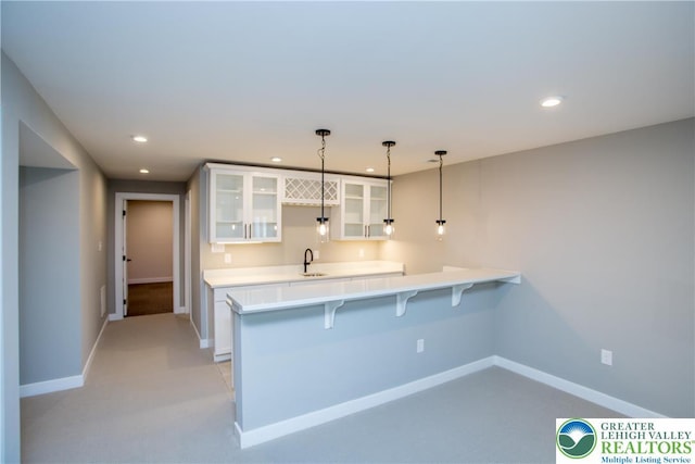 kitchen with white cabinets, a peninsula, glass insert cabinets, and light countertops