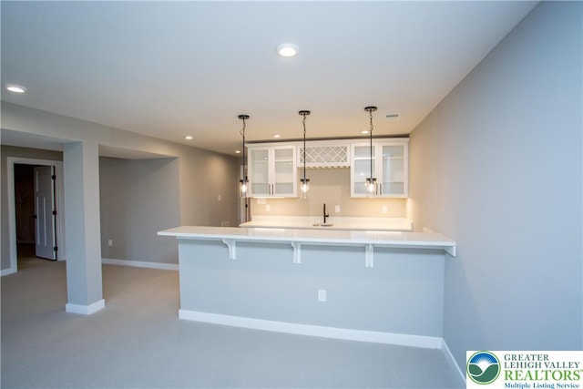 kitchen with a breakfast bar area, a peninsula, recessed lighting, and glass insert cabinets