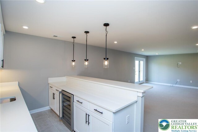 kitchen with beverage cooler, recessed lighting, baseboards, white cabinetry, and a peninsula