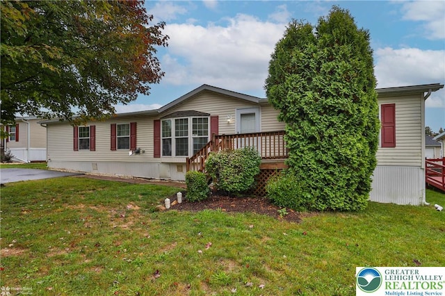 manufactured / mobile home featuring a wooden deck and a front lawn