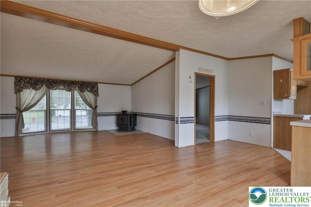 unfurnished living room featuring crown molding, a wood stove, a textured ceiling, and light wood-type flooring