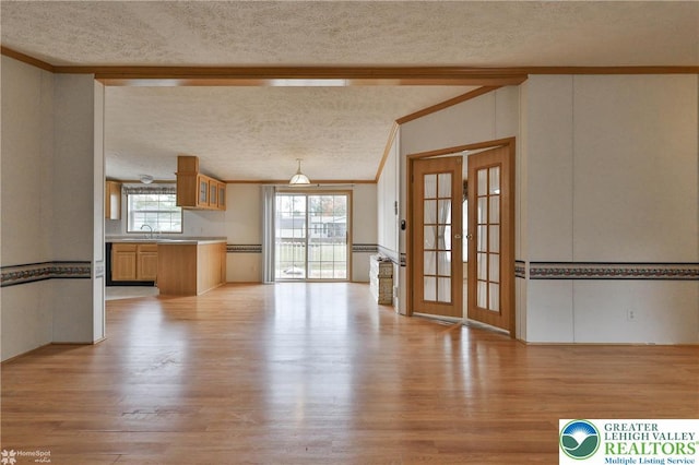 unfurnished living room with french doors, a textured ceiling, lofted ceiling, and light wood-type flooring