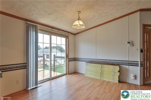 spare room featuring a textured ceiling, visible vents, ornamental molding, and wood finished floors