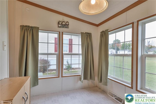 doorway featuring plenty of natural light, ornamental molding, vaulted ceiling, and visible vents