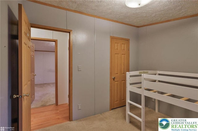 unfurnished bedroom with carpet floors, a textured ceiling, and ornamental molding