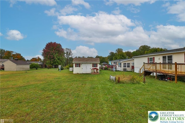 view of yard with a wooden deck, an outbuilding, and a shed