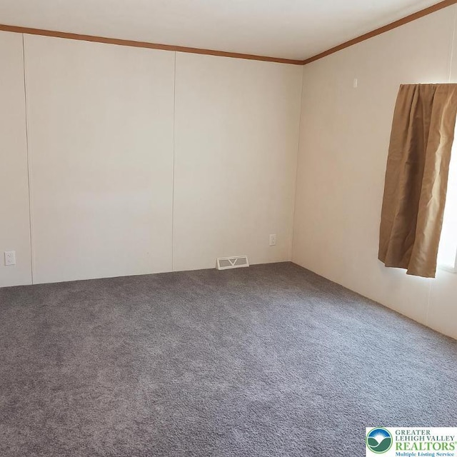 empty room with carpet floors, visible vents, and ornamental molding