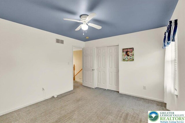 unfurnished bedroom with carpet, a ceiling fan, baseboards, visible vents, and a closet