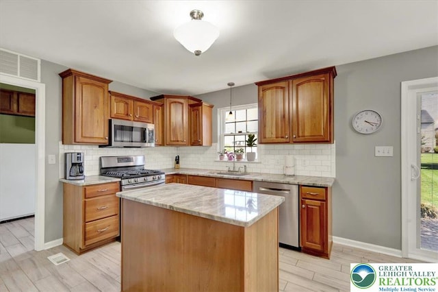 kitchen featuring light stone counters, a sink, appliances with stainless steel finishes, and tasteful backsplash