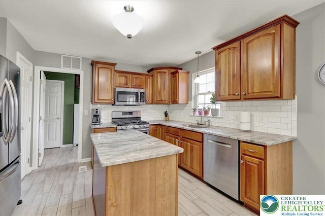 kitchen featuring a sink, light wood finished floors, a center island, stainless steel appliances, and visible vents