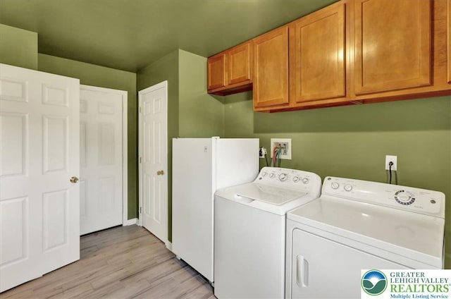 laundry room featuring light wood-type flooring, independent washer and dryer, and cabinet space