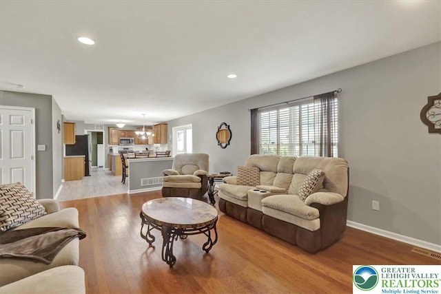 living room with visible vents, recessed lighting, light wood-style flooring, and baseboards