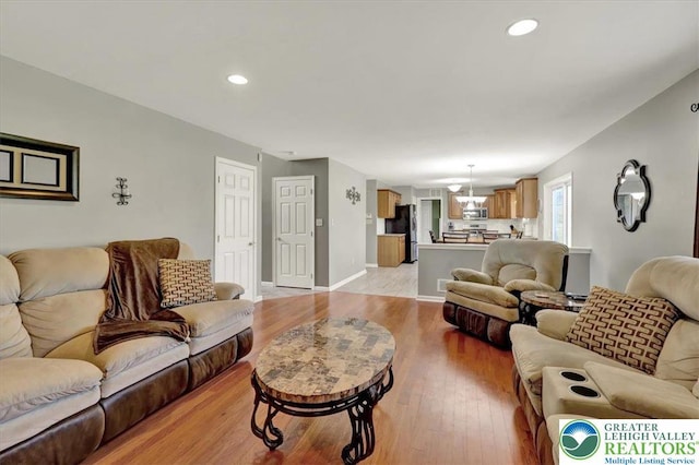 living area featuring recessed lighting, baseboards, and light wood-type flooring