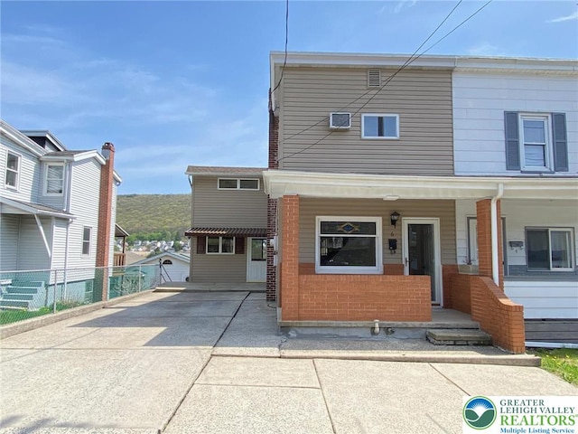 townhome / multi-family property with covered porch, fence, and concrete driveway