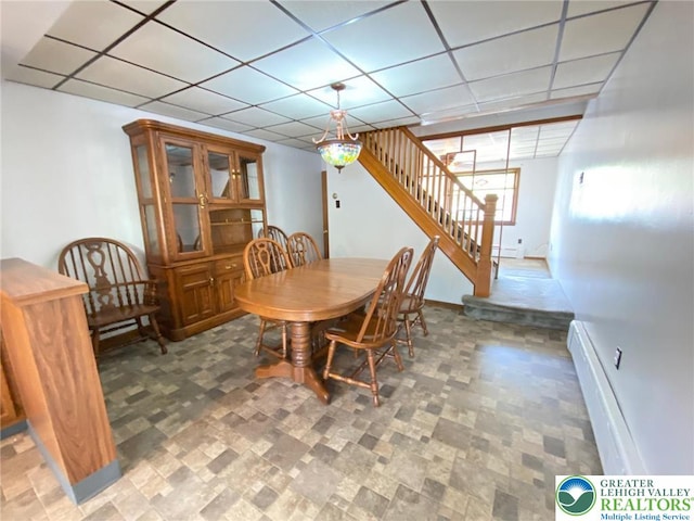 dining area with baseboards, stairs, baseboard heating, and a paneled ceiling
