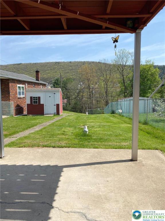 view of yard with fence, a patio, and an outbuilding