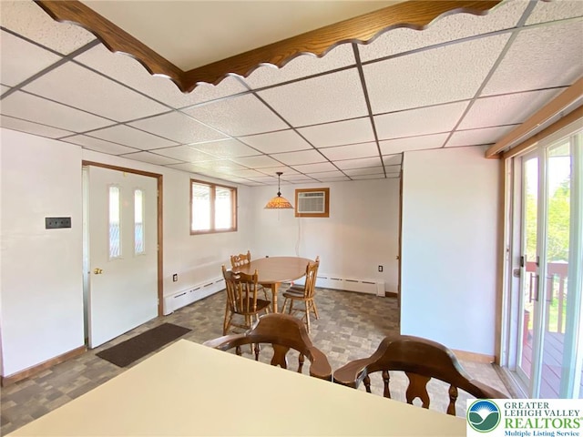 dining space featuring a drop ceiling, baseboard heating, and a wall mounted air conditioner