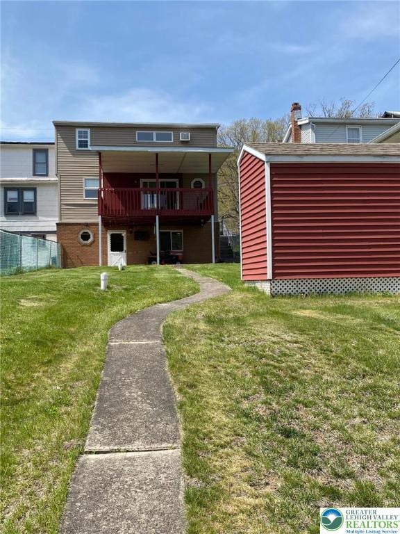 back of property with a lawn, a deck, and fence