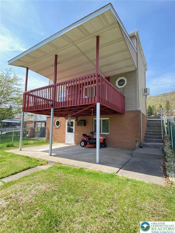 back of house featuring a patio, a lawn, fence, and brick siding