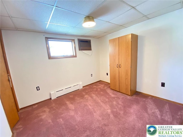 unfurnished bedroom featuring a paneled ceiling, a wall mounted air conditioner, baseboards, a baseboard heating unit, and carpet flooring