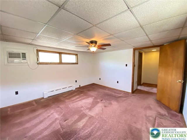basement featuring a paneled ceiling, baseboard heating, carpet, and a wall mounted air conditioner
