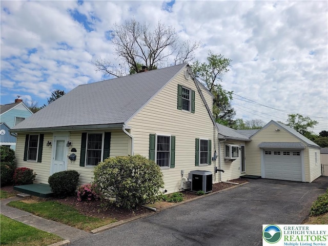 view of front of property with roof with shingles, a garage, a chimney, cooling unit, and driveway