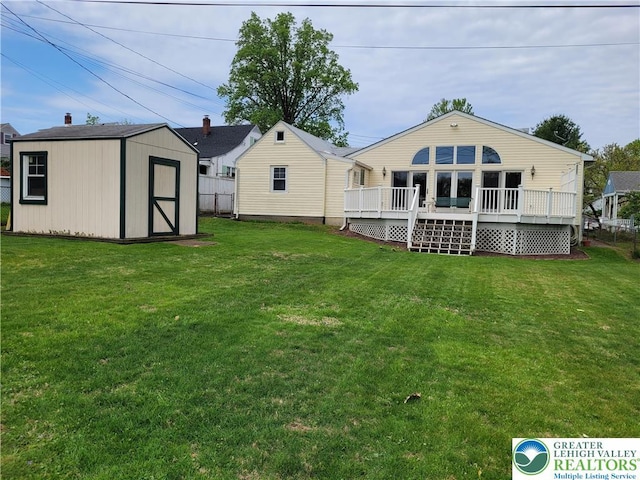 rear view of property featuring a lawn, a storage unit, an outdoor structure, and a deck