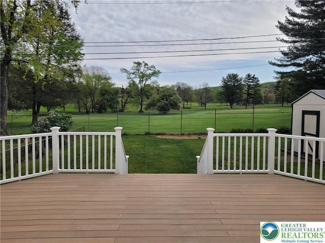 wooden terrace featuring a lawn, an outbuilding, and a storage shed