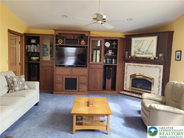carpeted living room featuring a ceiling fan and a tile fireplace