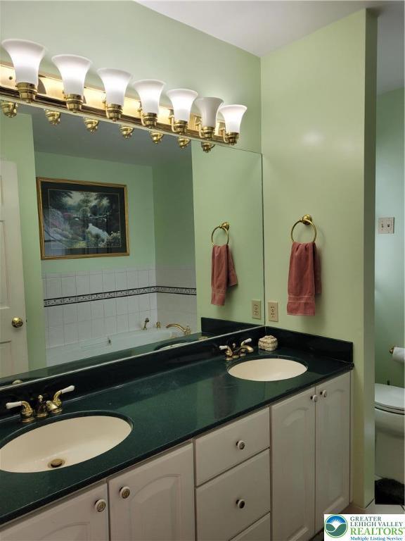 full bathroom featuring a sink, toilet, and double vanity