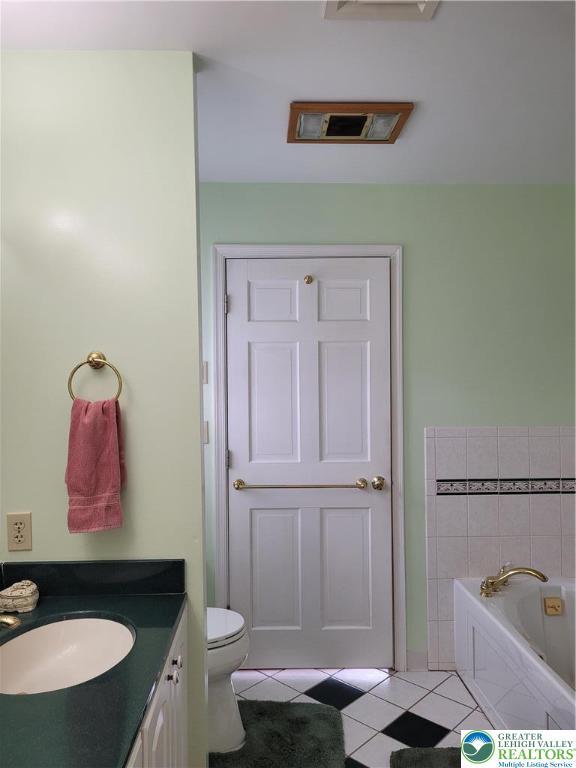 bathroom featuring tile patterned flooring, vanity, toilet, visible vents, and a garden tub