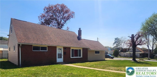 view of front of house featuring brick siding, a chimney, a shingled roof, and a front lawn