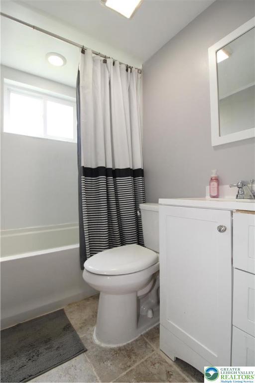 bathroom with vanity, shower / bath combination with curtain, and toilet