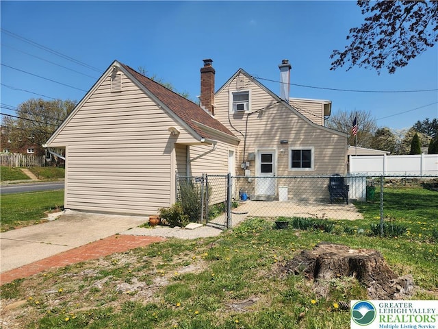 rear view of house featuring a lawn, a gate, fence, and a chimney
