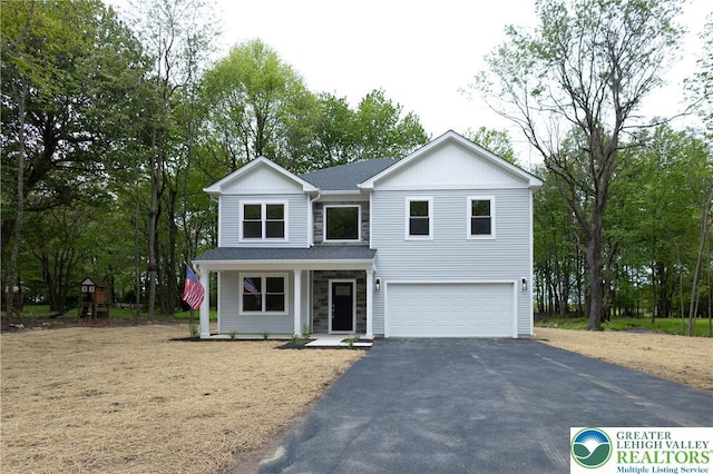 21 Piute Trl, Penn Forest Township, PA 18210 - traditional home featuring an attached garage, asphalt driveway, board and batten siding, a porch, and view of scattered trees